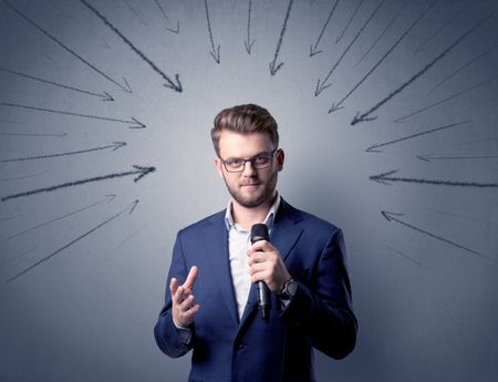 Businessman speaking into microphone with arrows pointing towards his head