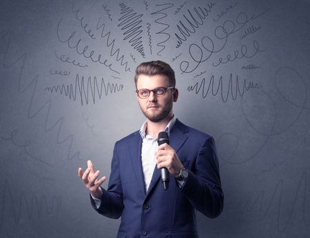 Businessman speaking into microphone with scribbles over his head 