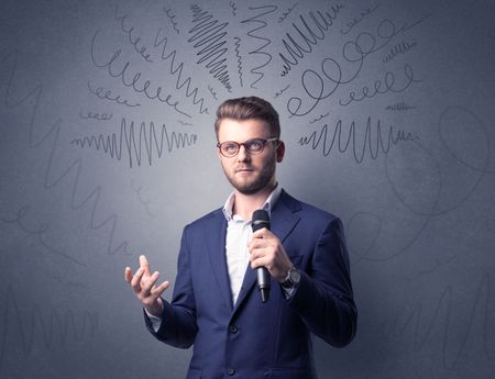 Businessman speaking into microphone with scribbles over his head