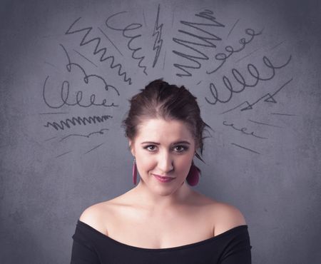 A cute female student making funny face expressions with pressure and problems in her head illustrated by drawn lines, marks and spirals on the urban wall background concept.