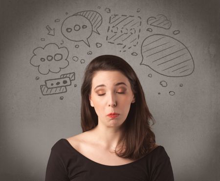 A cute female student making funny expressions with thoughts in her head illustrated by drawn chat bubbles on the urban wall background concept.