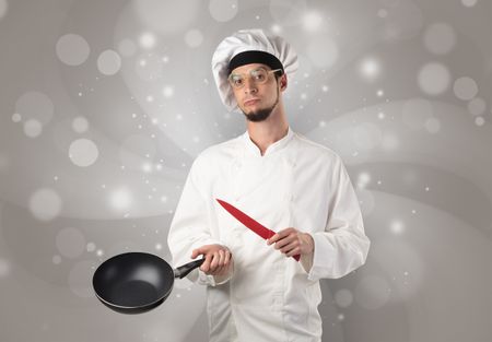 Male cook with kitchen tools and shiny grey wallpaper

