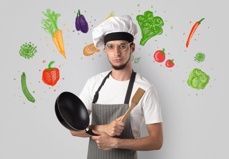 Bearded cook with colourful drawn vegetables on a white wallpaper
