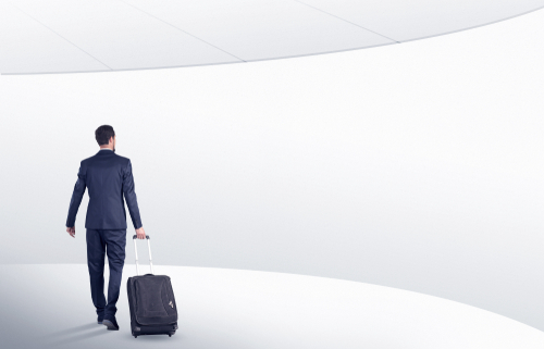 Businessman with back walking in a white waiting room with empty walls around
