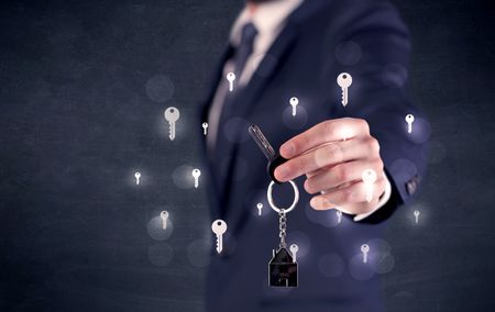 Businessman in suit holding keys with keys graphics around and dark background