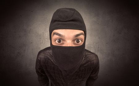 Burglar standing in black clothes and balaclava on his head.