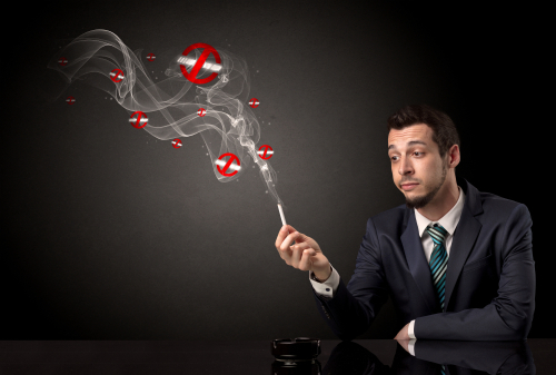 Businessman smoking with no smoking symbols nearby.