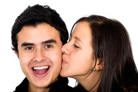 casual couple looking happy where the boyfriend is receiving a kiss from his girlfriend - smiling and isolated over a white background
