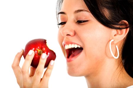 Beautiful casual woman about to bit an apple smiling and isolated over a white background