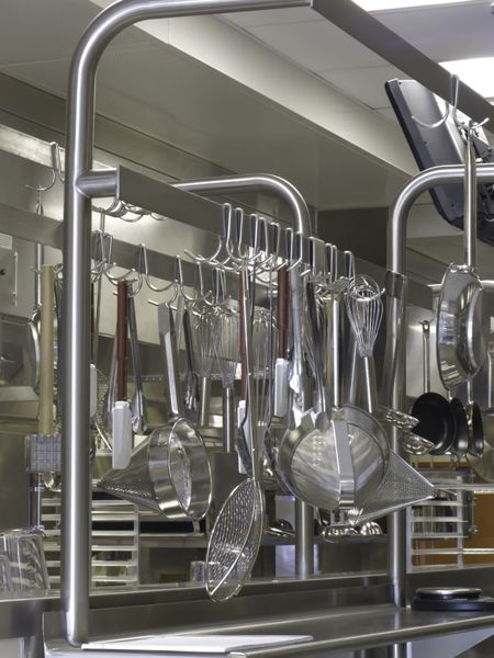 Aluminum kitchenware hanging in orderly hotel kitchen