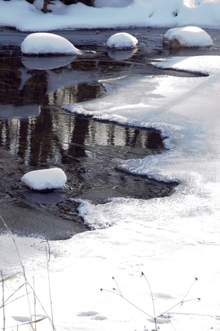 Snow-covered rocks in partly frozen creek