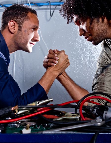 Two strong mechanics in a garage arm-wrestling
