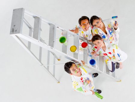 Group of painters holding their brushes and smiling with a ladder