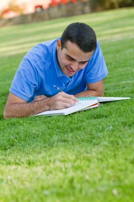 Casual man studying outdoors with a notebook