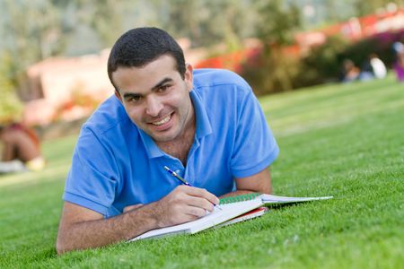 Casual man studying outdoors with a notebook