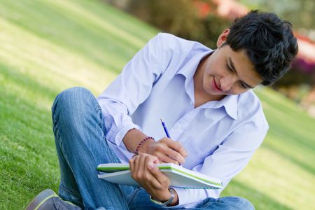 Casual man studying outdoors with a notebook