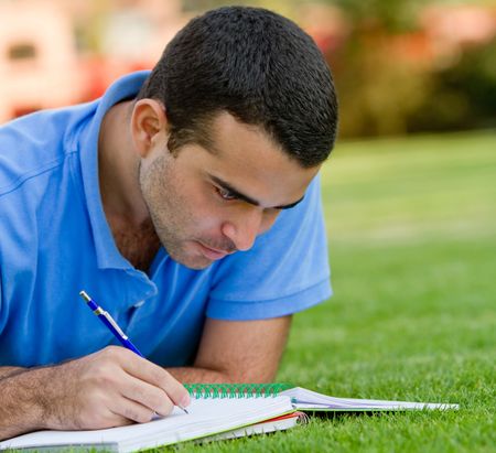 Casual man studying outdoors with a notebook