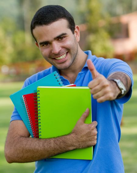 Male student smiling outdoors with thumbs-up