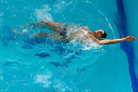 Professional male swimmer with hat and goggles at the pool