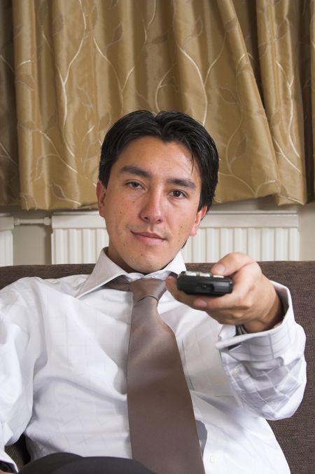 business man sitting on a sofa with the remote control