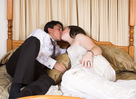 bride and groom on a bed kissing