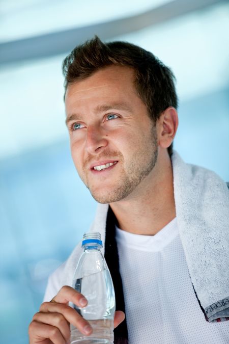 Handsome athletic man at the gym holding a bottle of water