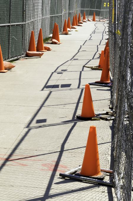 Fenced-in pedestrian walkway with safety cones in construction zone