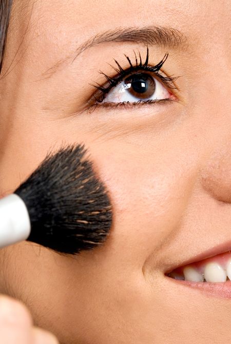 beautiful girl applying make up on her face