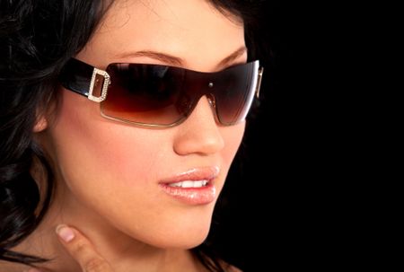 fashion or casual woman portrait wearing sunglasses giving a big smile over a black background