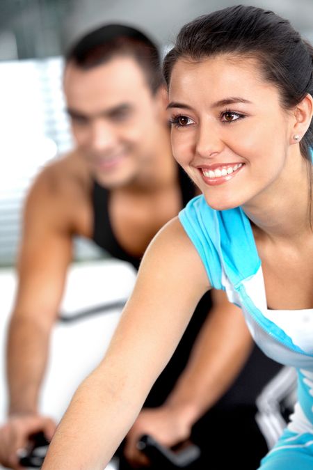 girl working out in a gym with a guy in the background