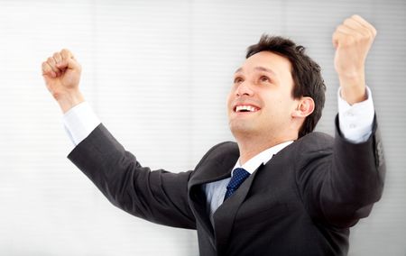 succesful business man in an office with his arms up