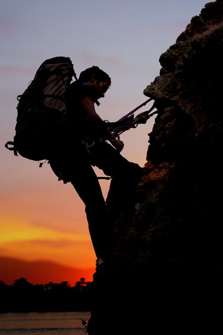 rock climber at sunset time going up a mountain