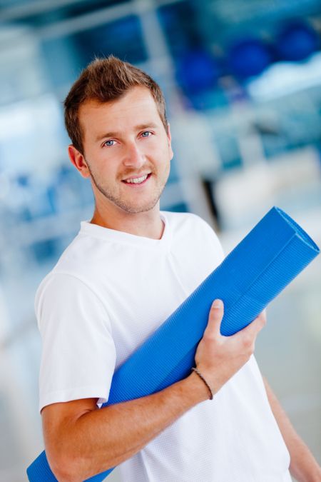 Handsome athletic man at the gym with a mat
