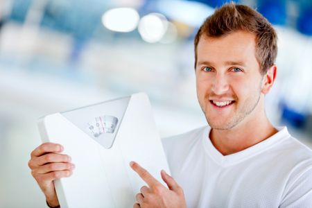 Man at the gym holding a scale - lose weight concepts