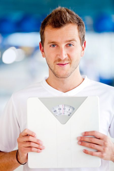 Man at the gym holding a scale - lose weight concepts