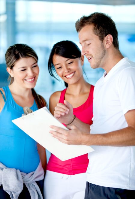 Beautiful women at the gym talking to their trainer