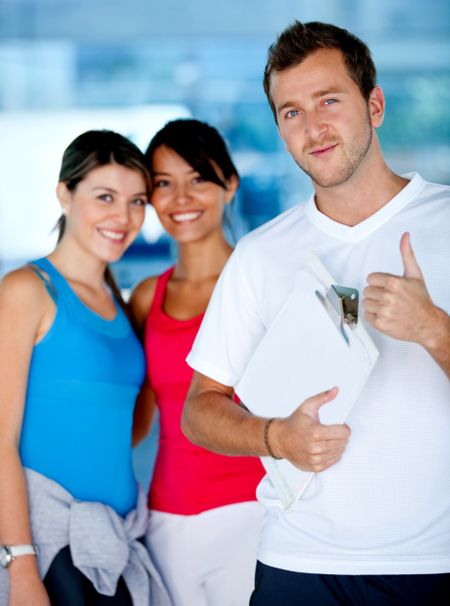 Trainer smiling with two beautiful women at the gym