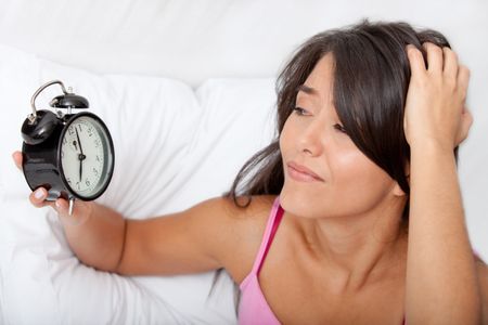 Woman waking up and running late looking at the alarm clock