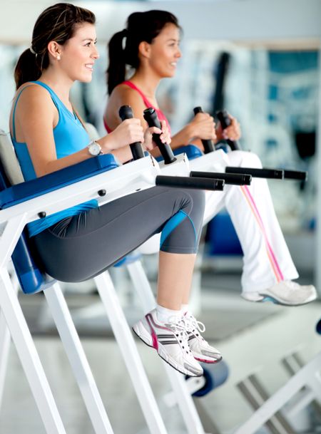 Women at the gym exercising their abs on a machine
