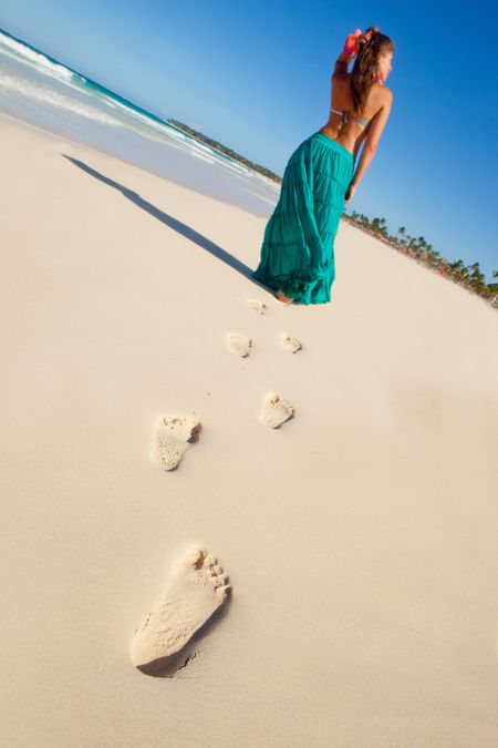 Hawaiian woman walking at the beach leaving footprints on the sand