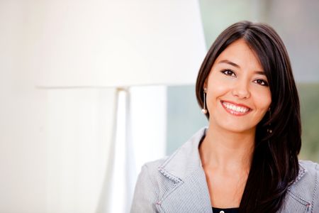 Casual woman at her apartment looking happy and smiling