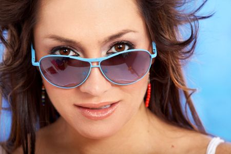 fashion or casual woman portrait wearing sunglasses giving a big smile over a blue background