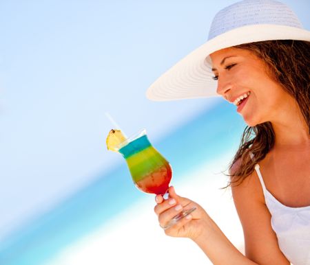Happy woman enjoying a tropical cocktail at the beach
