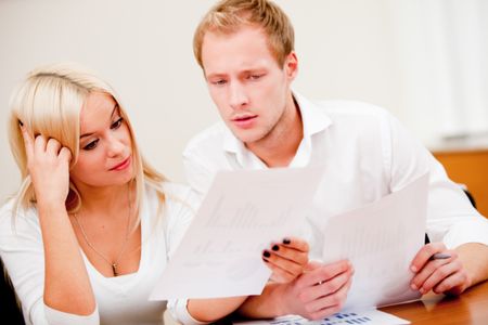 Business couple at the office checking numbers and looking worried