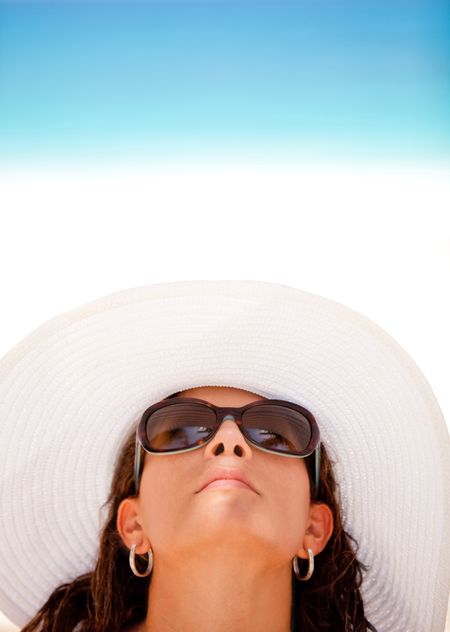 Woman enjoying the summer but protecting her skin with a hat and sunglasses
