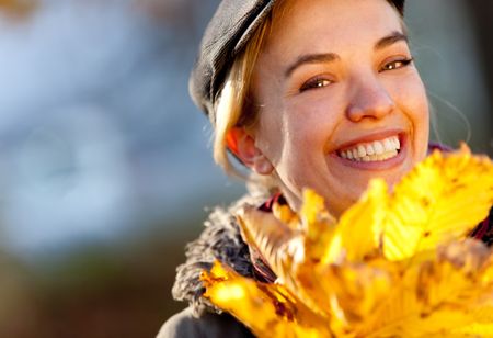 Happy autumn woman holding leaves and smiling outdoors