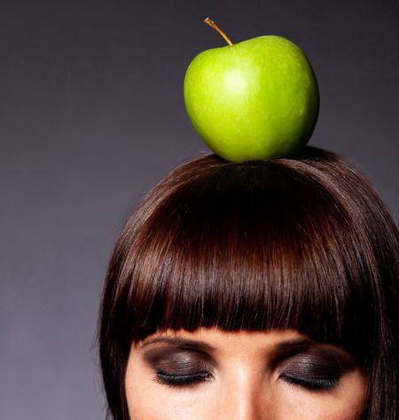 Woman with an apple on her head and closed eyes