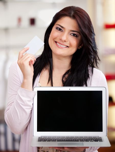 Woman holding a credit card and a laptop for online shopping
