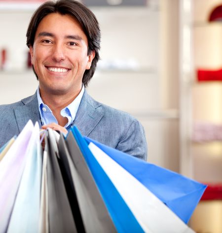 Male shopper with shopping bags looking happy