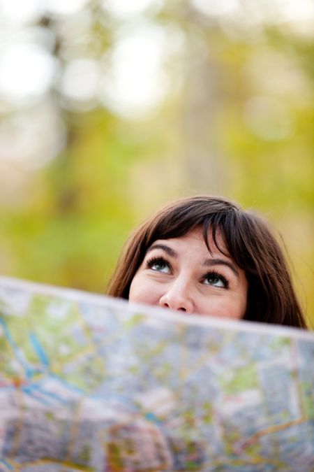 Woman exploring outdoors holding a map and looking lost